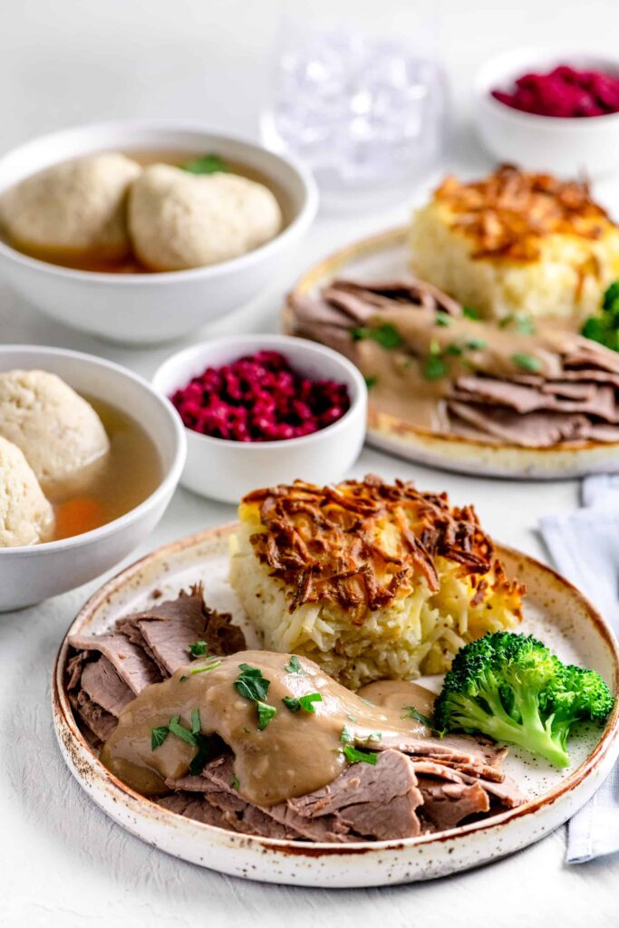 Passover Dinner plate with brisket, gravy, matzo ball soup, potato kugel and beet horseradish