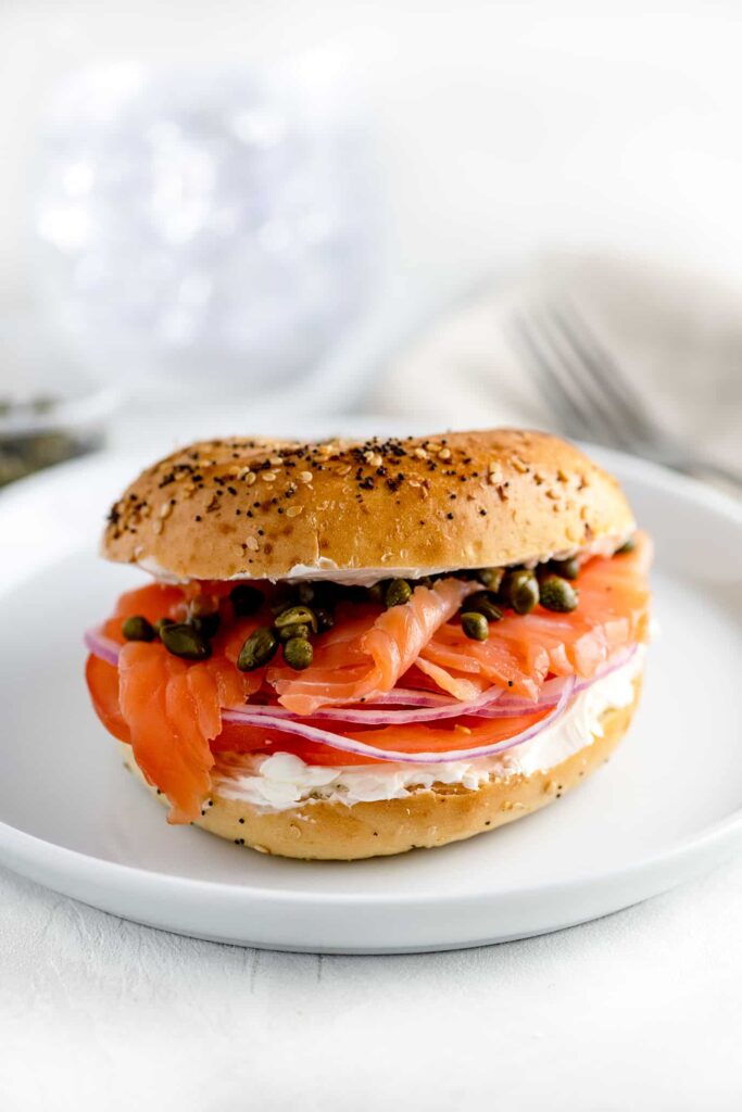 new york bagel with lox, capers and onions on white plate