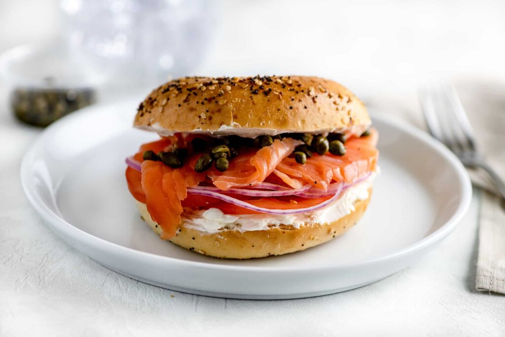 New York Bagel on white plate with lox, cream cheese and capers