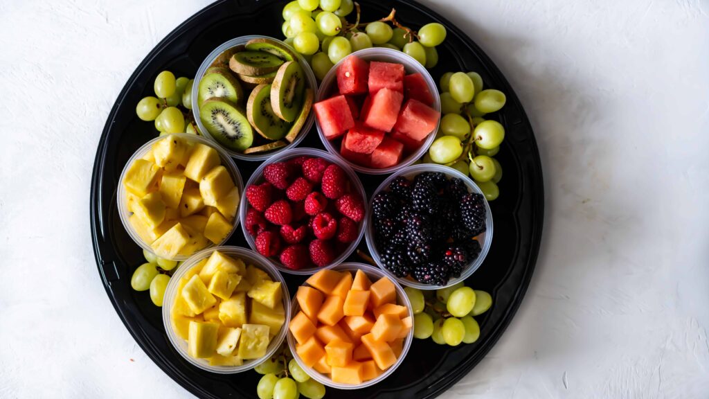 Fruit tray filled with berries, watermelon, grapes, kiwi, melon and pineapple