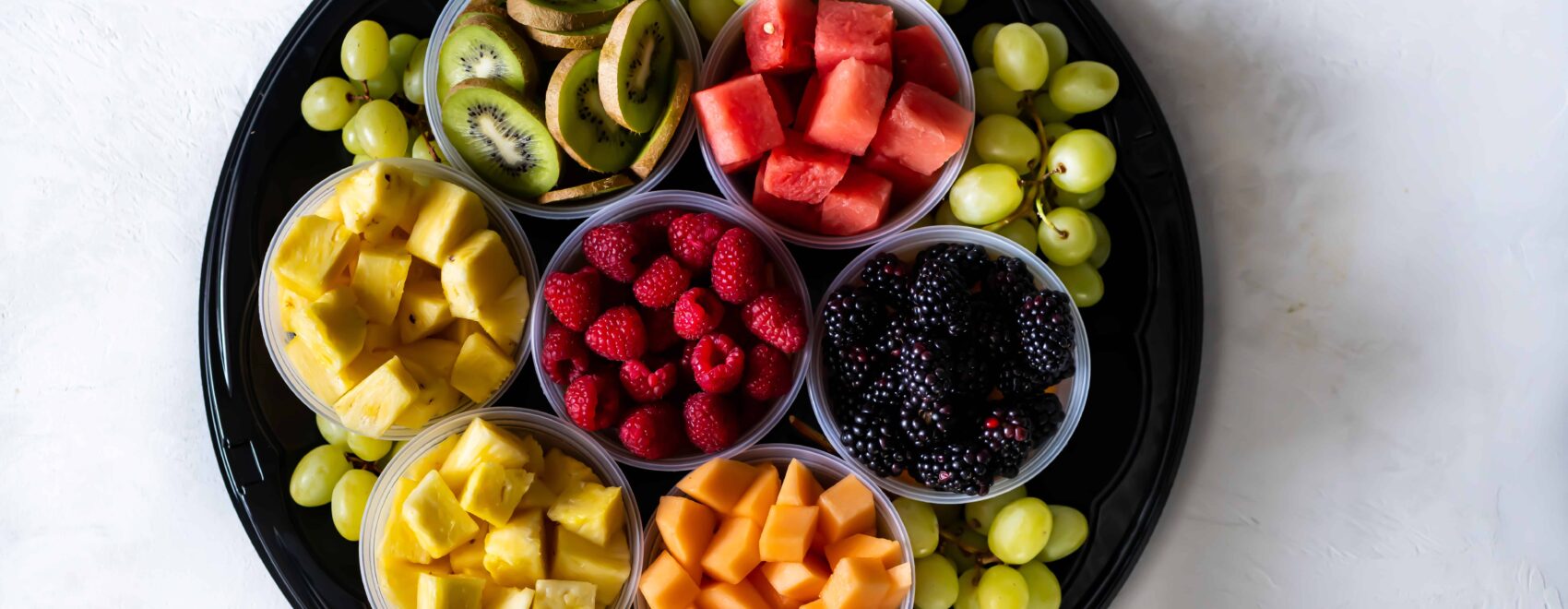 Fruit tray filled with berries, watermelon, grapes, kiwi, melon and pineapple
