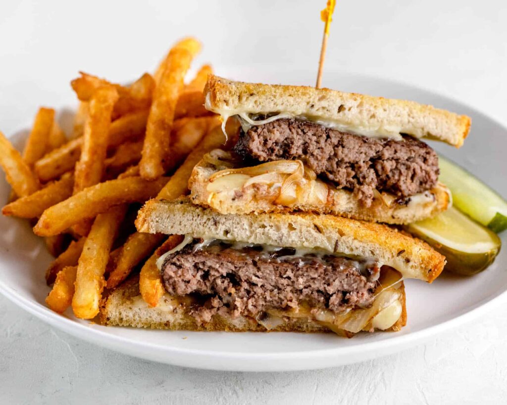 Patty melt on grilled rye bread with crispy fries