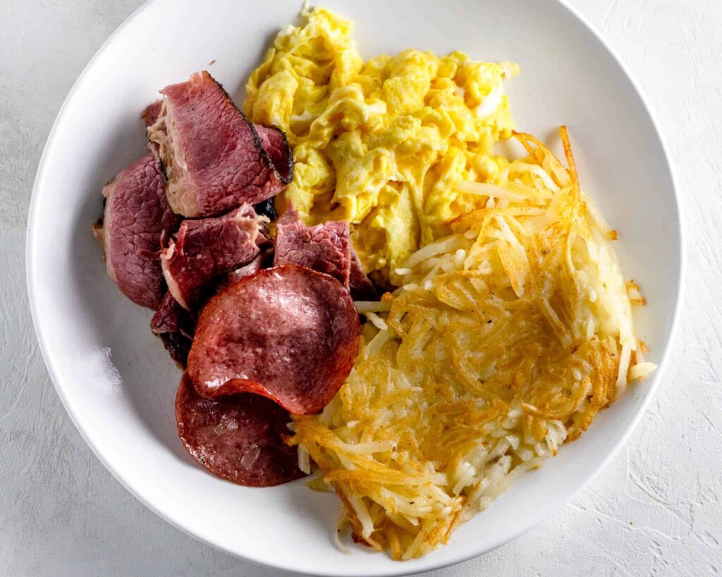 deli meat and eggs with hash browns on a plate