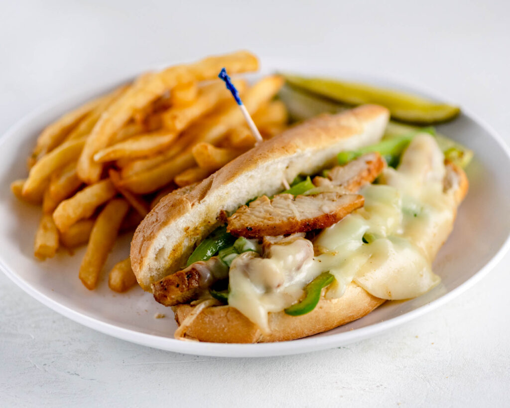 Chicken Philly Cheesesteak on white plate with fries