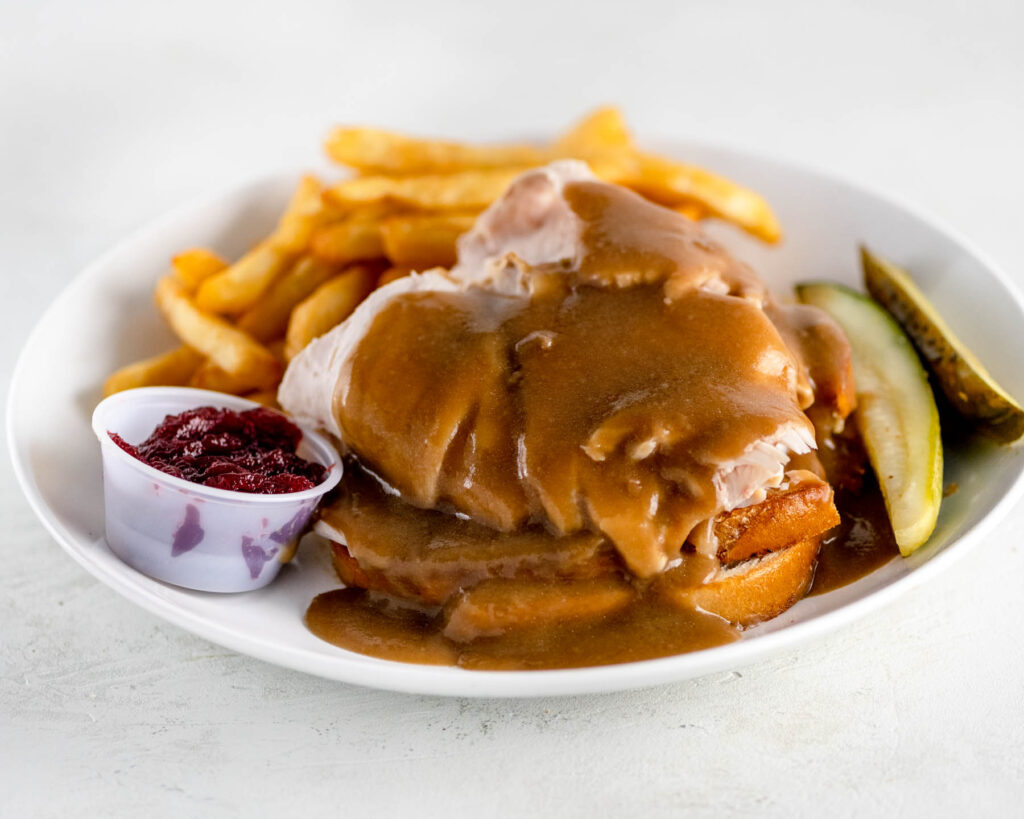 Roasted Turkey with Gravy and cranberry sauce on a white plate with fries