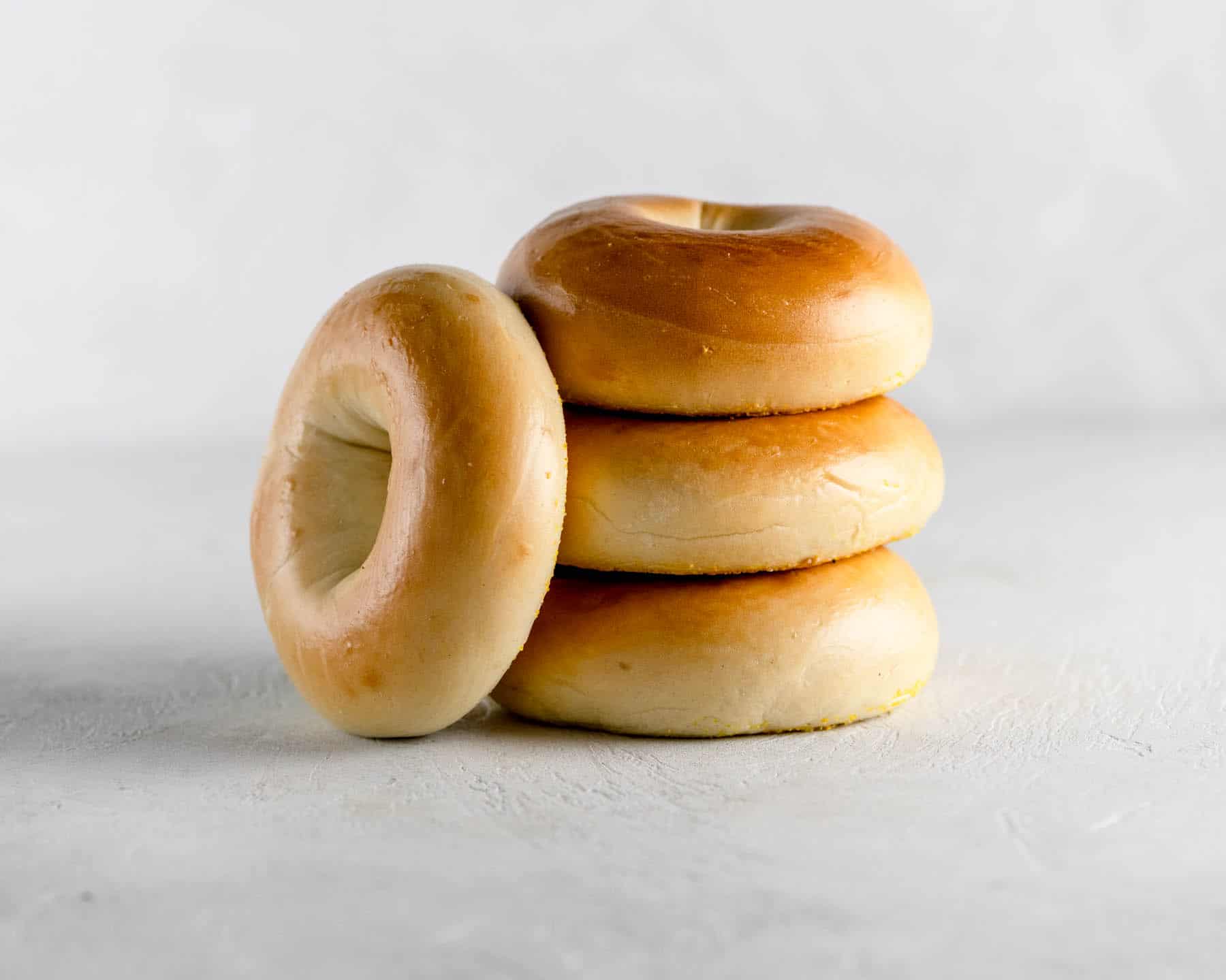 4 plain new york bagels stacked on a gray table