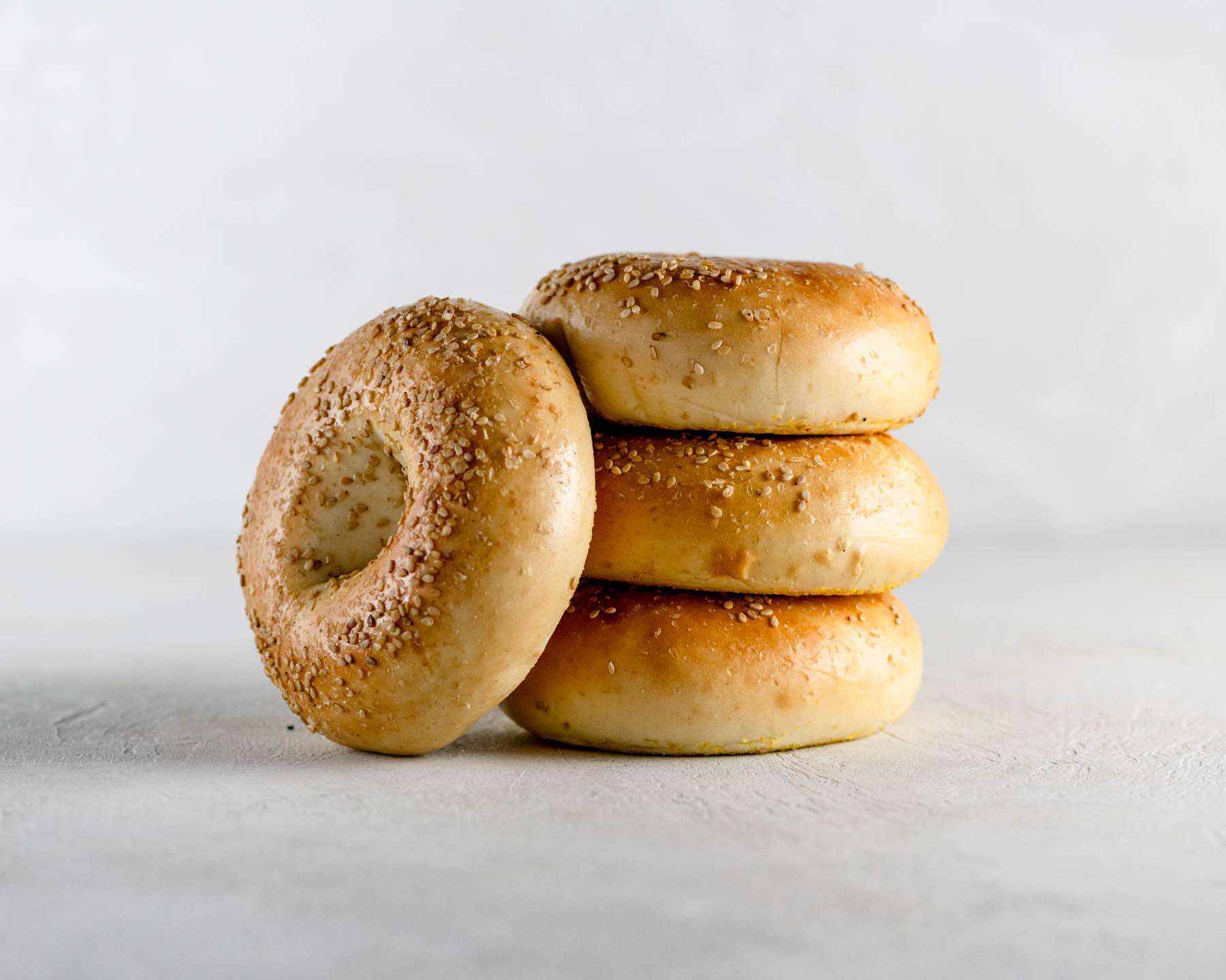 4 new york sesame bagels stacked on a gray table