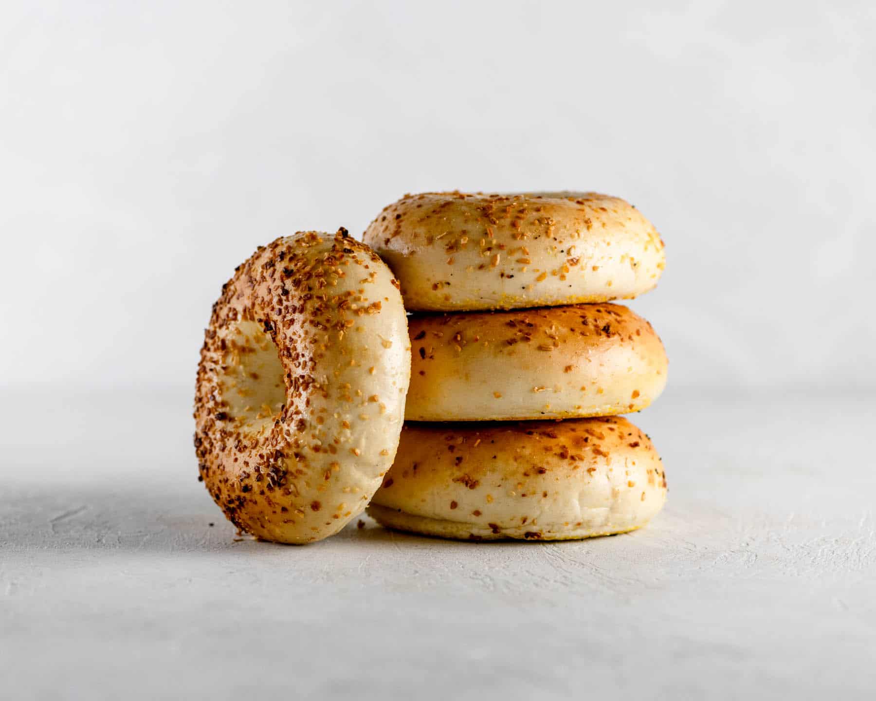 4 new york onion bagels stacked on a gray table
