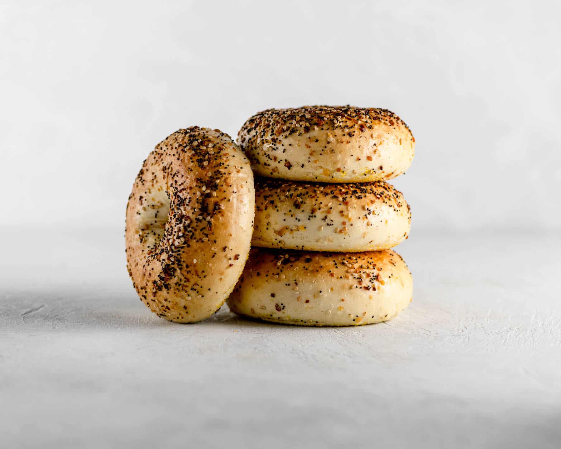 4 new york everything bagels stacked on a gray table