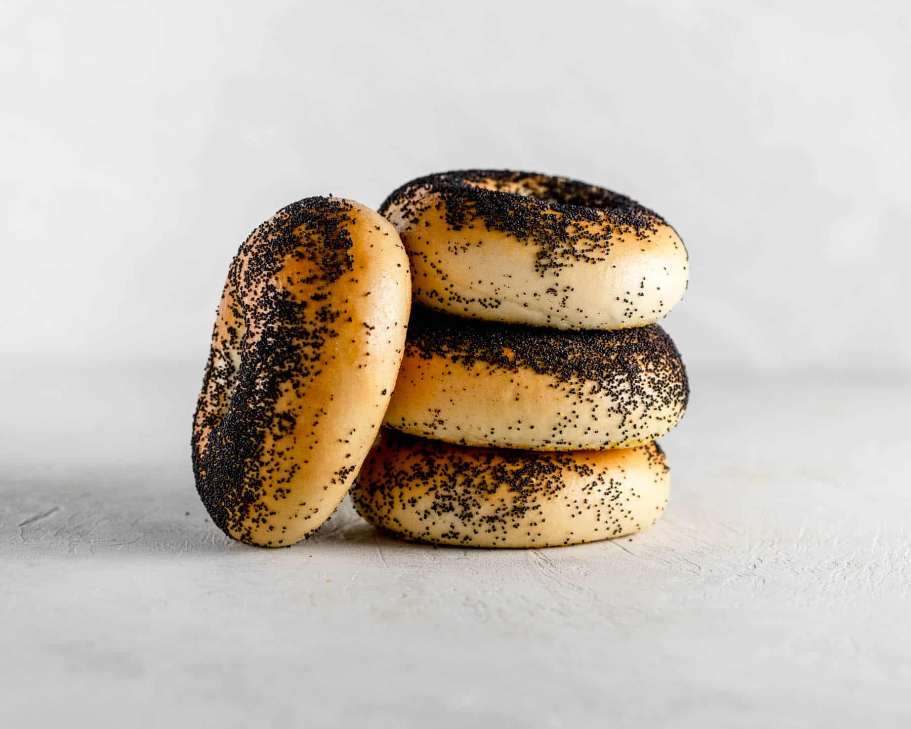 4 new york poppy bagels stacked on a gray table